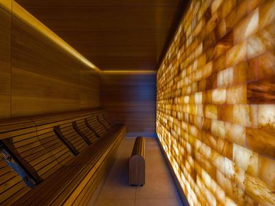 Schmaler Wellnessraum mit hölzerner Bank und beleuchteter Salzwand