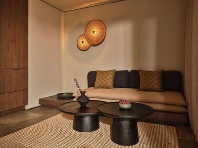 Gemütliche Hotellounge mit brauner Couch, Teppich und modernen Wandlampen in warmen Tönen.