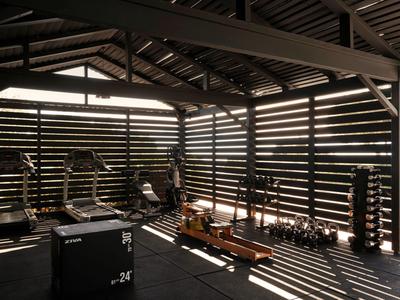 Überdachter Fitnessbereich mit modernen Geräten und Sonnenlicht, ideal für Hotelgäste.