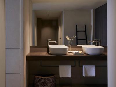 Moderne badkamer met twee wastafels, handdoeken en indirecte verlichting.