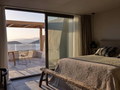 Gezellige slaapkamer met toegang tot een terras en uitzicht op zee bij zonsopgang.