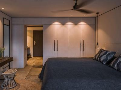 Moderne slaapkamer met groot bed, ingebouwde kasten en plafondventilator.