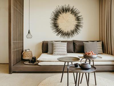 Moderne woonkamer met comfortabele bank, ronde tafels en decoratieve wandversiering.