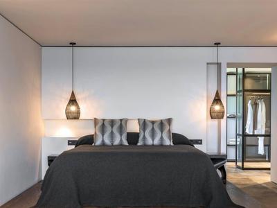 Moderne slaapkamer met tweepersoonsbed, twee hanglampen en minimalistische inrichting.