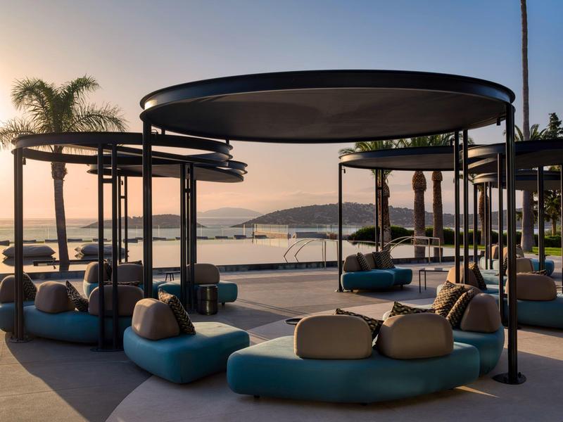 Moderne loungerooms met ronde zonwering en kussens op het strand bij zonsondergang.