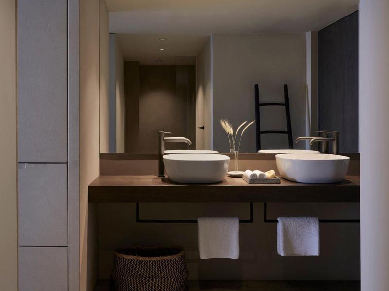 Moderne badkamer met twee wastafels, handdoeken en indirecte verlichting.