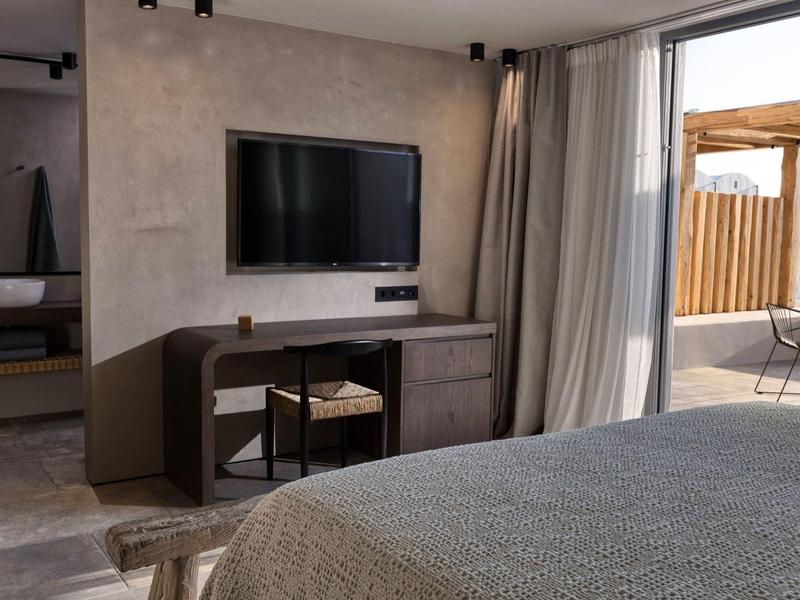 Modern hotelkamer met tv, bureau en toegang tot een balkon.