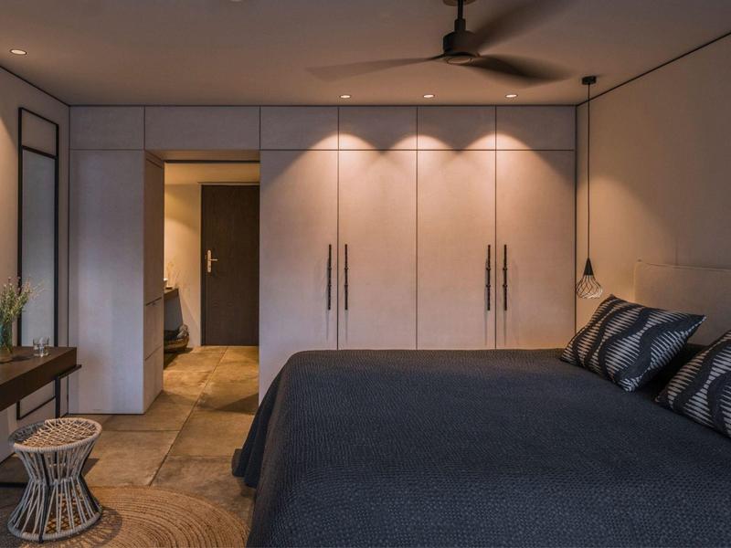 Moderne slaapkamer met groot bed, ingebouwde kasten en plafondventilator.