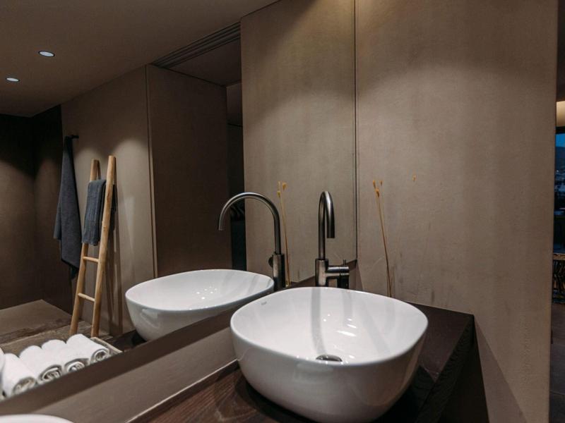 Moderne badkamer met ronde wastafel, vrijstaand bad en bruine muren.