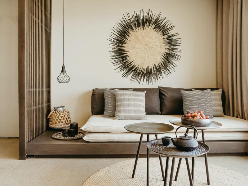 Moderne woonkamer met comfortabele bank, ronde tafels en decoratieve wandversiering.