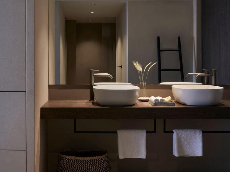 Moderne badkamer met twee opzetkommen en grote spiegel bij warm licht.