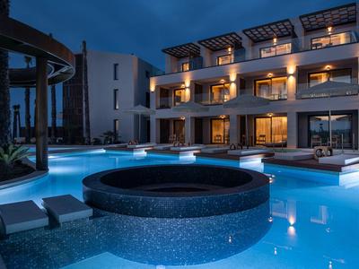 Modern hotel with illuminated outdoor pool and hot tub at night.
