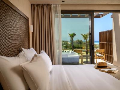 Modern hotel room with large bed and view of terrace and sea