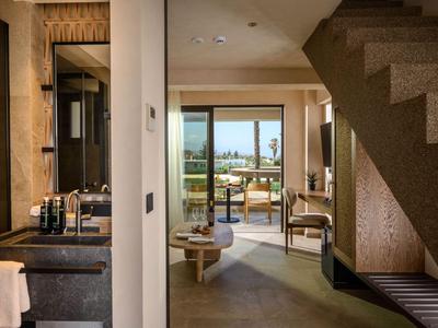 Modern hotel area with bathroom, chairs, and view of terrace with sea view