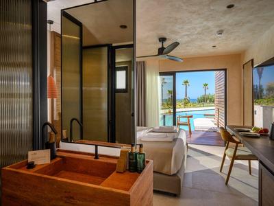 Habitación de hotel con interior moderno y vista a una piscina con palmeras.