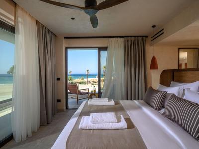 Habitación de hotel moderna con vista al mar, cama doble y terraza con zona de estar.