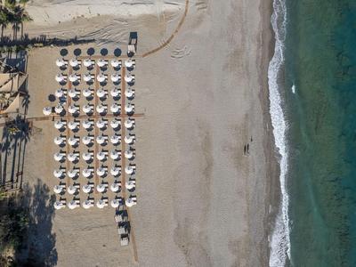 Vista aérea de una playa con sombrillas ordenadas y mar azul.