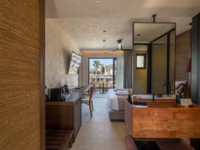 Habitación de hotel moderna con balcón, escritorio y mobiliario elegante.