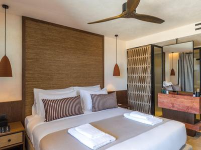 Habitación de hotel moderna con cama doble, mesitas de noche y gran espejo.