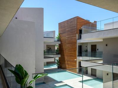 Complejo hotelero moderno con líneas limpias, detalles de madera y barandillas de vidrio durante el día.