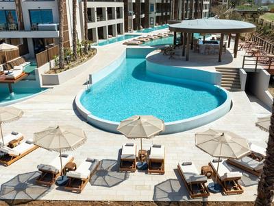 Modern hotel pool with round lounge chairs, umbrellas, and integrated pool bar area.
