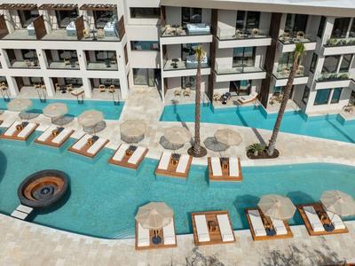 Hotel pool with lounge chairs and umbrellas in front of a multi-story hotel building
