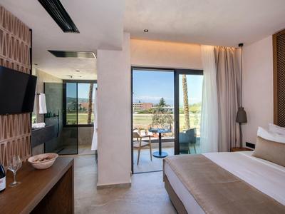 Moderní hotelový pokoj s manželskou postelí, balkonem a výhledem na slunečnou terasu.