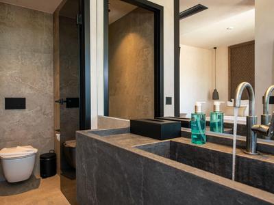 Moderní koupelna s kamenným umyvadlem a závěsným WC.