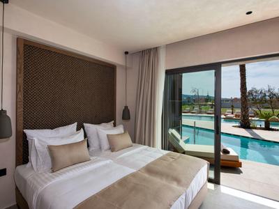 Moderní hotelový pokoj s manželskou postelí, velkými okny a výhledem na venkovní bazén.