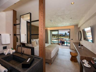 Moderní hotelový pokoj s postelí, terasou a elegantním dřevěným a černým nábytkem.