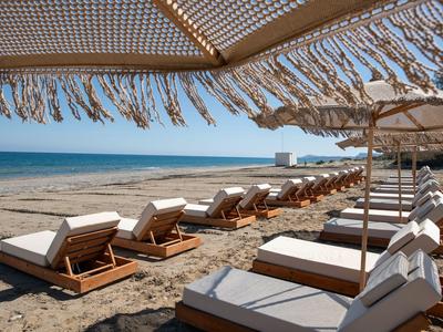 Pohodlná plážová lehátka pod slunečníky na jemném písku u moře.