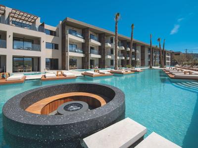 Modern hotel pool with lounge chairs and fire pit under blue sky