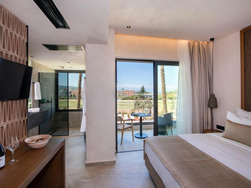 Moderní hotelový pokoj s manželskou postelí, balkonem a výhledem na slunečnou terasu.