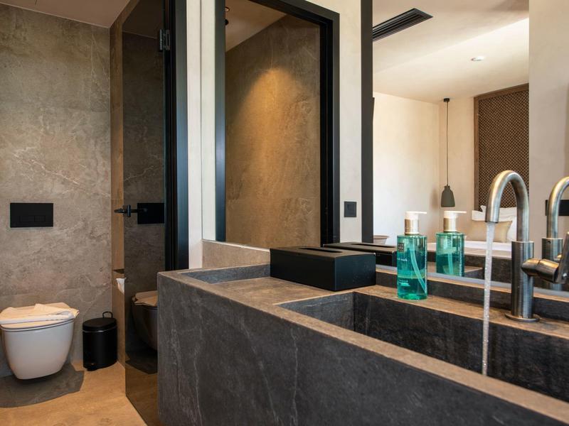 Moderní koupelna s kamenným umyvadlem a závěsným WC.