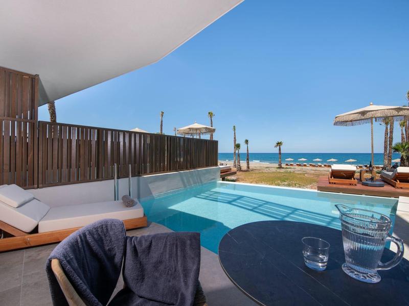 Soukromý bazén s výhledem na moře, lehátka a jasná modrá obloha.