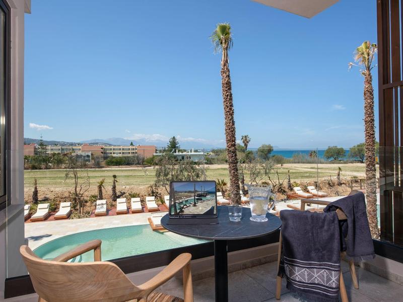 Hotelová terasa s bazénem, výhledem na moře a lehátky pod jasně modrou oblohou.