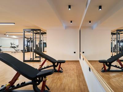 Moderner Fitnessraum mit verstellbarer Trainingsbank und Reflexionsspiegel an der Wand.