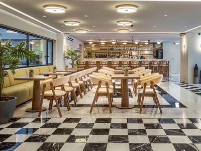 Modern eingerichteter Hotelrestaurantbereich mit Holzmöbeln und Schwarz-Weiß-Marmorboden.