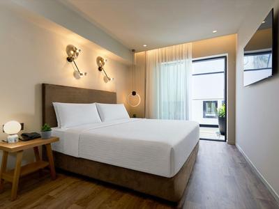 Modernes Hotelzimmer mit Doppelbett, Holzboden und großem Fenster mit Blick auf Terrasse.