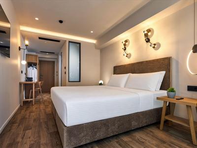 Modern eingerichtetes Hotelzimmer mit großem Bett, Holzboden und minimalistischem Design.