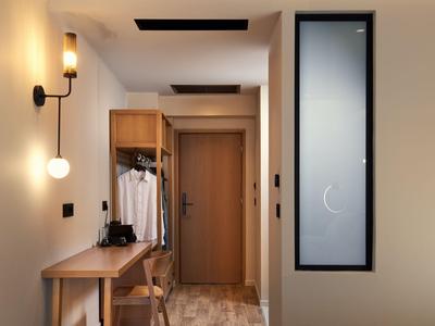 Schlichte Hotelflur mit Holztür, Garderobe und warmweißer Beleuchtung.