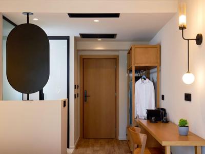 Moderner Hotelflur mit Holztür, offenem Kleiderschrank und Schreibtisch mit Dekoration.