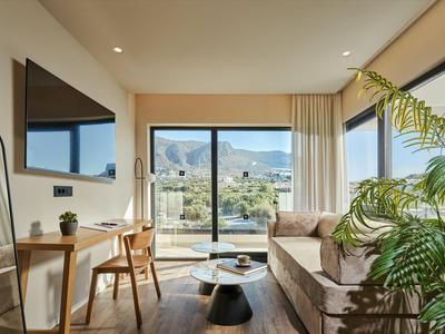Modernes Hotelzimmer mit Sofa, Schreibtisch und großem Fenster mit Bergblick.
