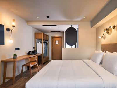 Modernes, gemütliches Hotelzimmer mit großem Bett, Schreibtisch und warmem Licht.
