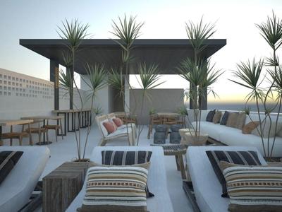 Nowoczesny salon na zewnątrz z sofami, poduszkami i roślinami na tarasie na dachu o zachodzie słońca.