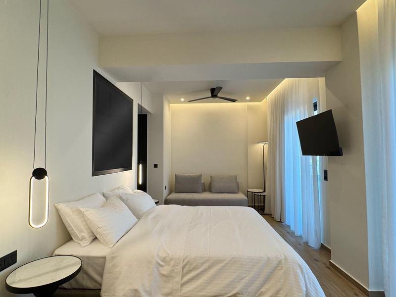 Modernes Hotelzimmer mit Doppelbett, zwei Fernsehern und minimalistischem Design.