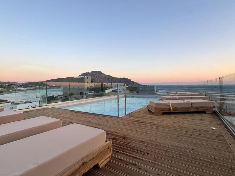 Dachterrasse mit Pool, Liegen und Blick auf das Meer bei Sonnenuntergang.