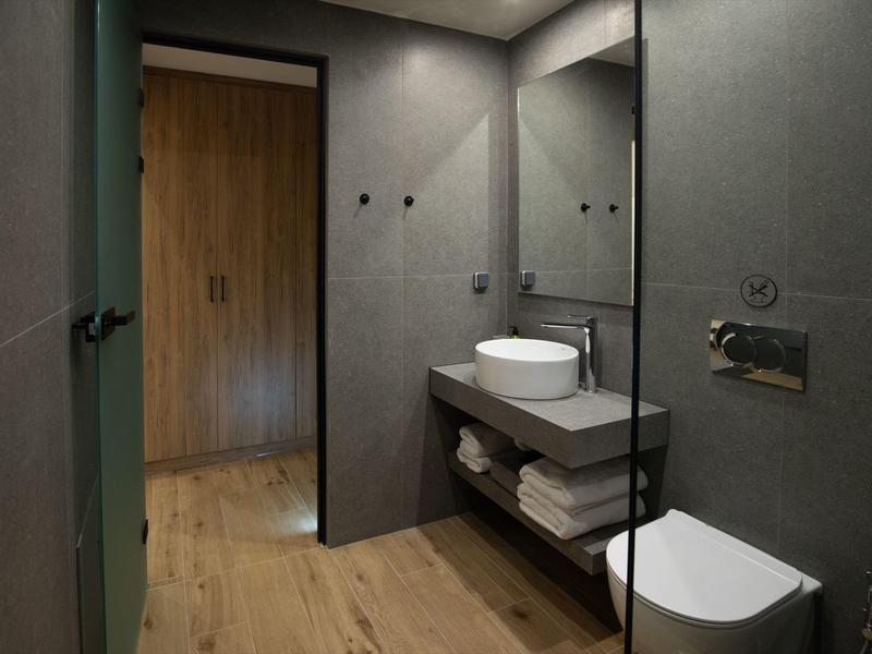 Modernes Badezimmer mit grauen Wänden, Waschtisch, Spiegel und Toilette auf Holzboden.