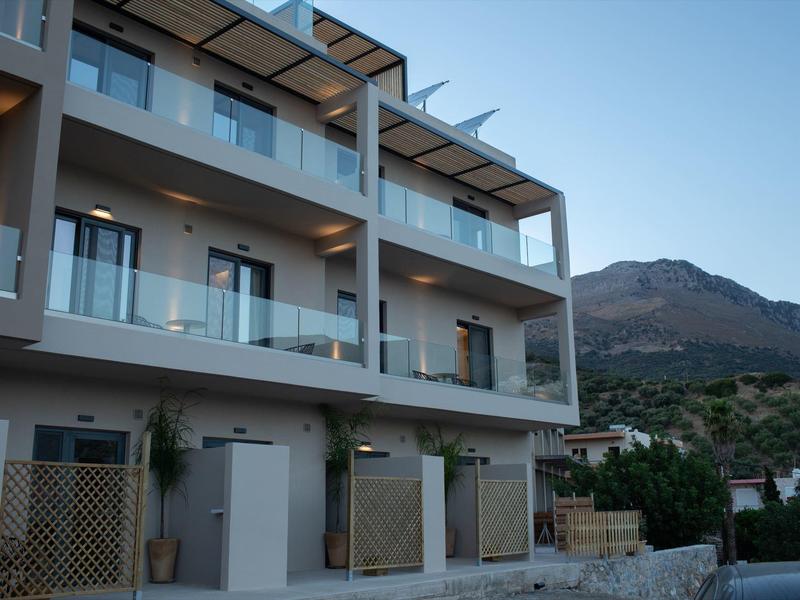 Moderner Hotelbau mit Balkonen vor Bergkulisse bei klarem Himmel.