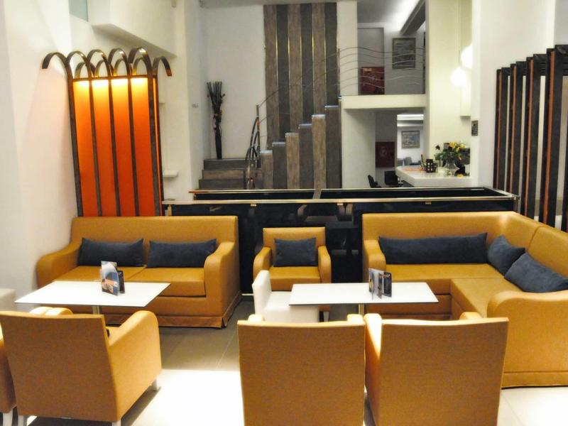 Moderne Lounge mit orangefarbenen Sitzmöbeln, weißen Tischen und hellem, großzügigem Raum.